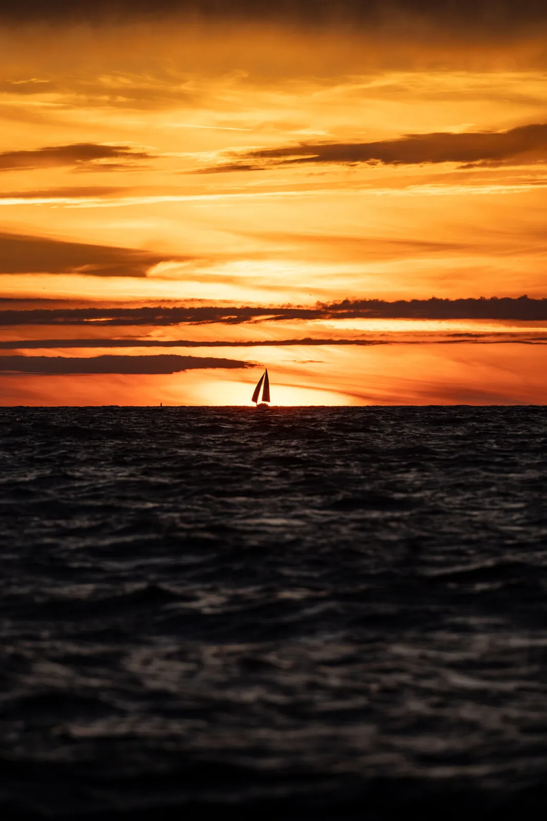 Sailboat under a banded orange sky